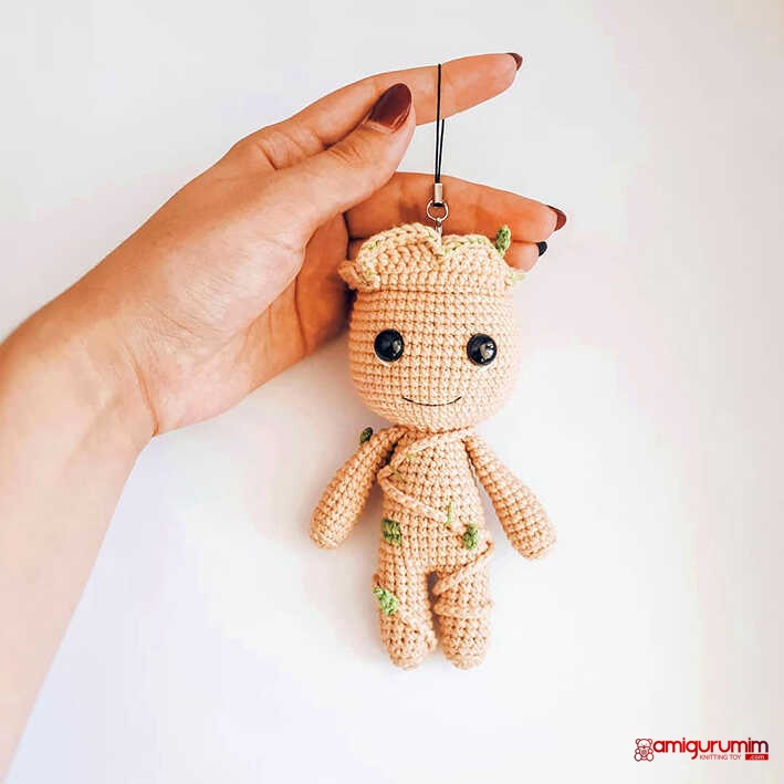 Baby Groot amigurumi crochet keychain held in hand with cute tree details, small handmade character toy, free crochet pattern for gift or bag charm.